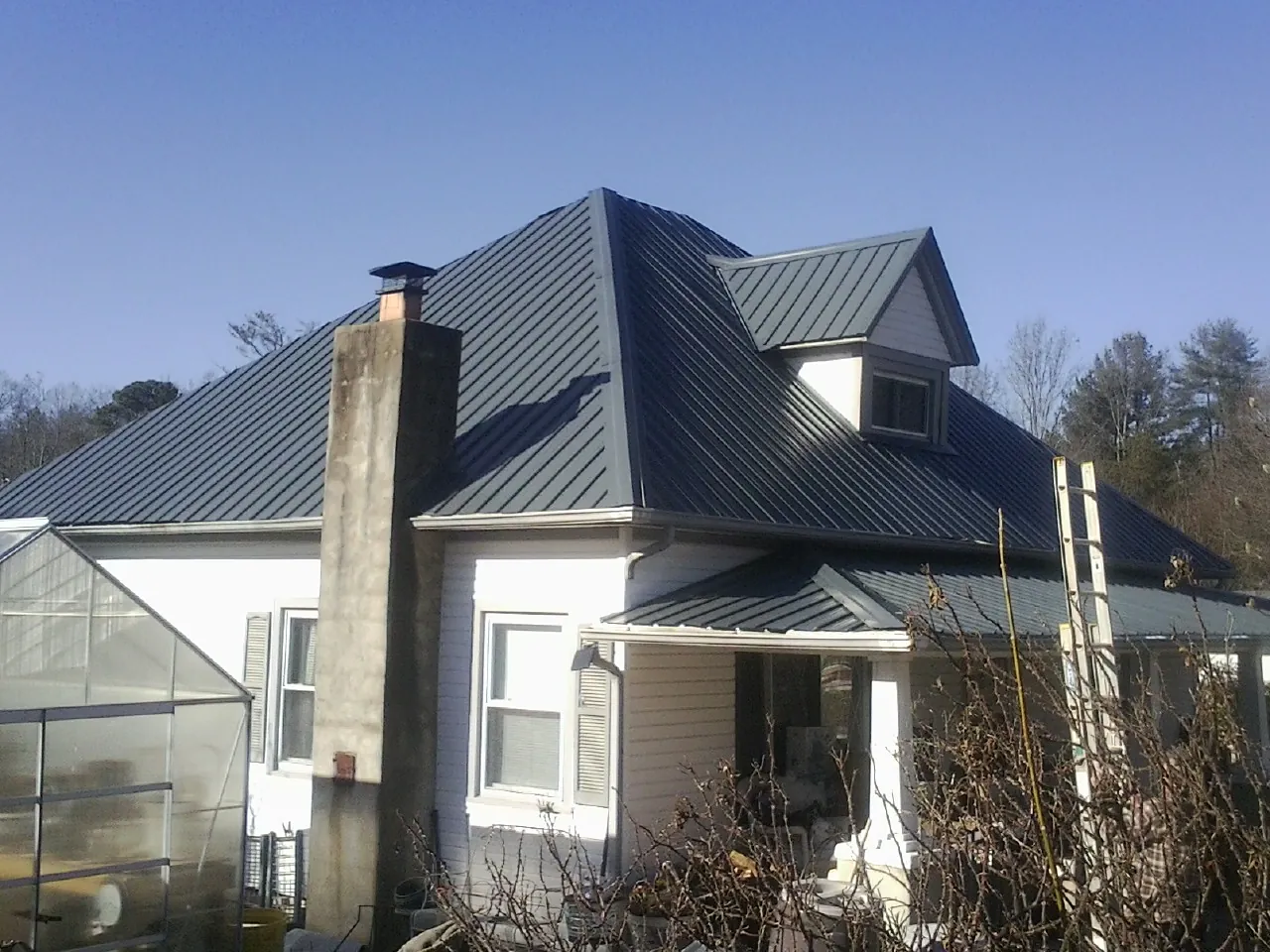 Dark blue standing seam metal roof on a white farmhouse with dormer — Slate & Tile Roof Repair by Roofing Brothers in Pierrepont Manor