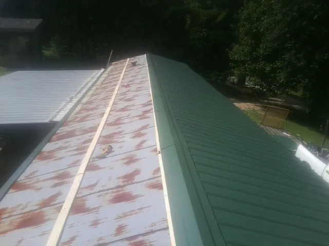 Old rusted panels beside newly installed green metal roofing — Wind Damage Roof Repair by Roofing Brothers in Pierrepont Manor