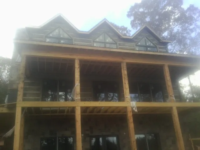 Dormers and porch framing on a large log home under construction — Roof Coating work by our crew in Pierrepont Manor