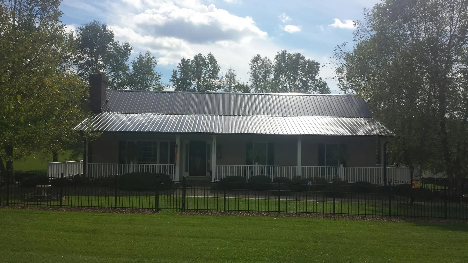 Gray metal roof on a brick ranch with a full width front porch — Gutter Guard Installation work by our crew in Pierrepont Manor
