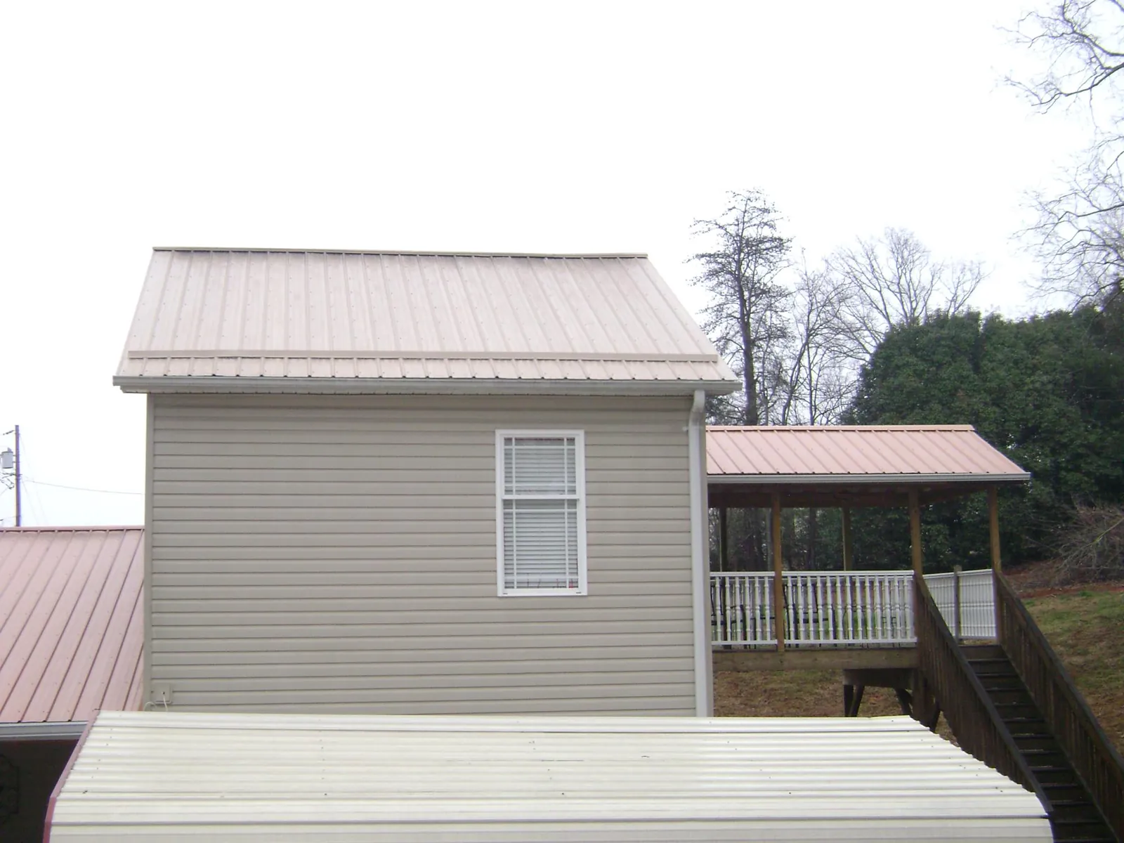 Tan metal roofs on a two story addition and attached porch, from a Roof Replacement job in Pierrepont Manor